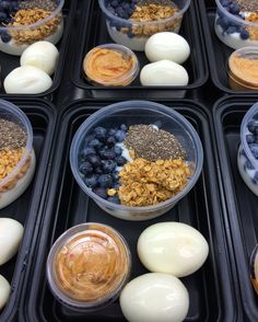 several plastic containers filled with different types of breakfast foods on top of black trays