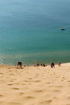 several people are walking on the beach near the water