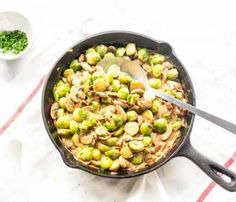 brussel sprouts and mushrooms are in a skillet with a spoon