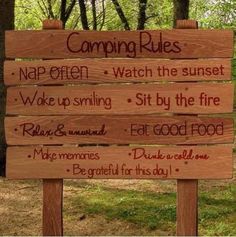 a wooden sign that says camping rules next to some trees in the background with words written on it