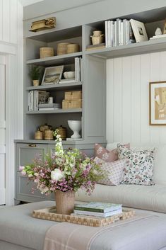 a living room filled with lots of furniture and flowers on top of a coffee table