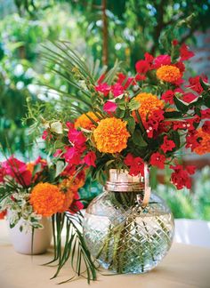 vases filled with flowers sitting on top of a table next to potted plants