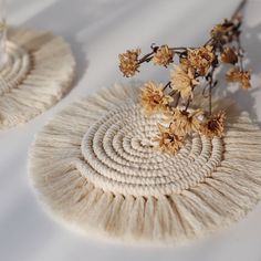 two pieces of art made out of yarn and flowers on top of each other, sitting on a white surface