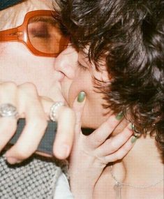 a man and woman kissing each other while wearing sunglasses