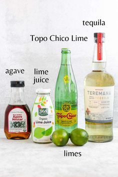 the ingredients to make an alcoholic cocktail are shown in three different bottles, including limes and tequila