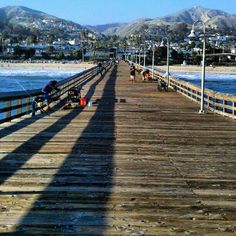 people sitting on benches at the end of a pier