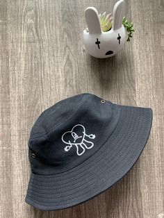 "Bad bunny bucket hat has heart with frown. Image is made with white heat transfer vinyl or black heat transfer vinyl depending on the hat color. One size fits most.Hat circumference 56-58cm/22.1-22.8\" and Brim measures 2 ~ 2.25 inches. Black hat is bit smaller then beige hat. Care instructions: spot clean only (Disclaimer:Flower pot not included)" Bunny Bucket Hat, Beige Hat, White Heat, Bad Bunny, Bucket Hats, Black Hat, Transfer Vinyl, Heat Transfer Vinyl, Flower Pot