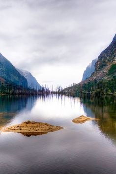 an island in the middle of a lake surrounded by mountains