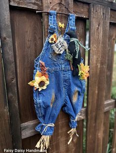 an old pair of denim overalls with sunflowers and skulls hanging on a fence