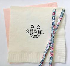 two napkins with floral designs on them and one has a monogrammed horseshoe