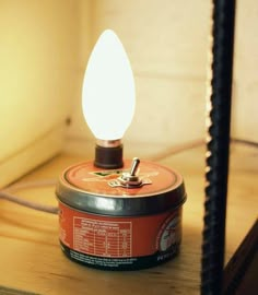 an orange can sitting on top of a wooden table next to a light fixture with a white bulb