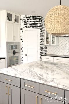 a kitchen with white cabinets and marble counter tops in front of a basket hanging over the stove