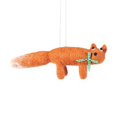 an orange stuffed animal hanging from a string with a green bow on it's head