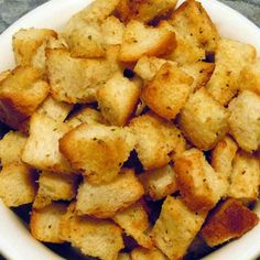 a white bowl filled with croutons on top of a table