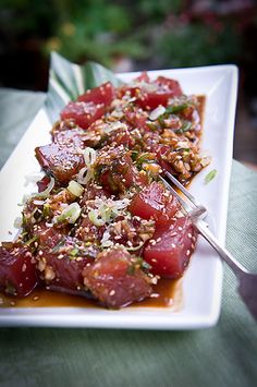 a white plate topped with meat covered in sauce and garnished with toppings