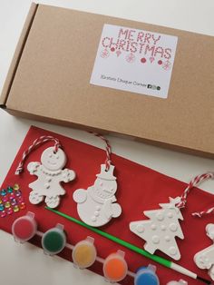 a box filled with christmas decorations next to paint tubes and glue sticks on top of a table