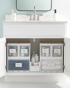 a bathroom sink with several containers under the faucet, and a mirror above it