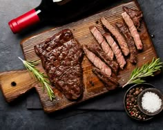 steaks on a cutting board with a knife and fork next to the chopping board