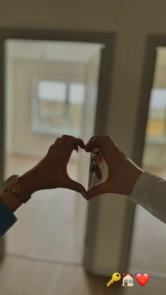 two people making a heart shape with their hands in front of an open room door