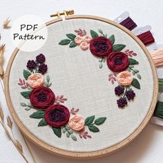 an embroidery pattern with flowers and leaves on it, surrounded by thread spools