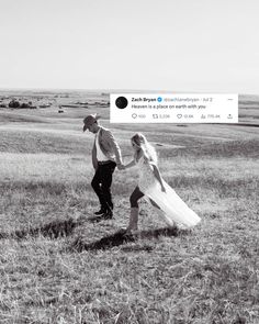 a man and woman walking through a field holding hands