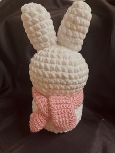 a crocheted bunny with a pink bow on it's head sitting in a black bag