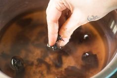 a person is stirring something in a pot with some brown liquid on the stove top