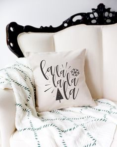 a pillow that says let it snow on top of a white chair next to a blanket