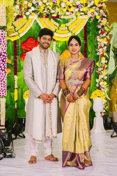 two people standing next to each other in front of a flower covered stage with flowers on it