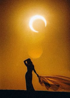 a woman is standing in front of the sun with her veil blowing in the wind