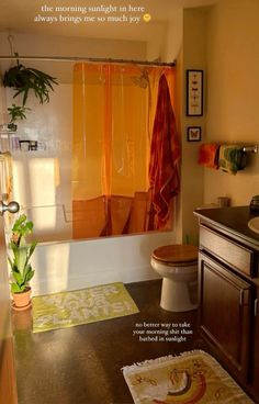 an orange shower curtain in a bathroom next to a toilet and sink with a rug on the floor