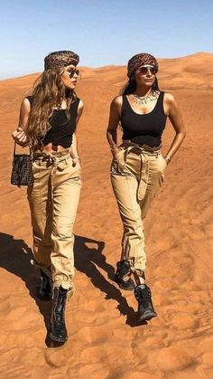 two women walking in the desert with their hands on their hipss