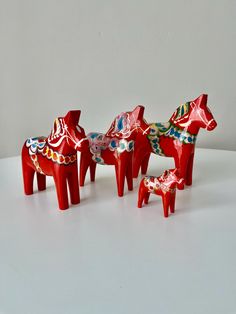 three red ceramic horses sitting on top of a white table