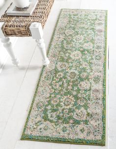 a green and white rug on the floor next to a wicker table with vases