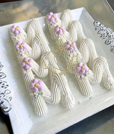 a white plate topped with cookies covered in frosting and flowers on top of a table