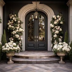 two large vases filled with white flowers sitting on the steps to a front door