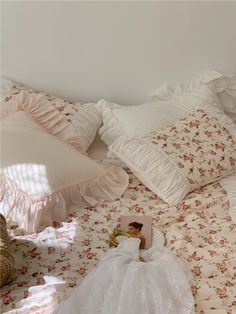 a woman in a white dress laying on top of a bed next to pillows and blankets