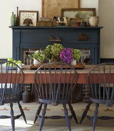 a dining room table with four chairs and an old fireplace in the backround