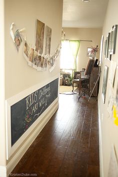 a long hallway with pictures hanging on the wall and wooden floors in front of it