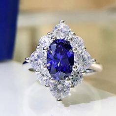 a blue and white diamond ring sitting on top of a table