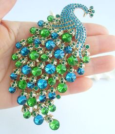 a peacock brooch with green and blue jewels