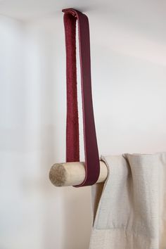 a white curtain with a red ribbon hanging from it's side next to a wooden pole