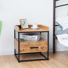 a nightstand with books on it next to a bed