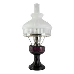 an old fashioned table lamp with a purple glass shade on the top and black base