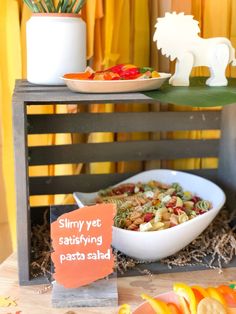 a table topped with plates and bowls filled with food next to a sign that says slimy yet saidrying pasta salad