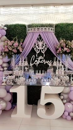 the table is set up with purple and white balloons, silver candles, and flowers