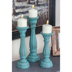 three teal candles are sitting on a table