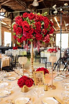 the centerpieces are adorned with red roses and gold candlesticks as well