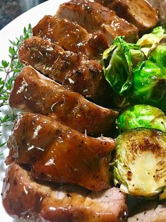 meat and vegetables on a white plate with sauce drizzled over the top