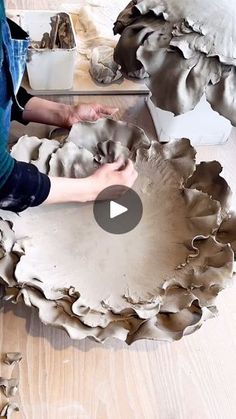 a person sitting on the floor working on a piece of art that looks like oysters